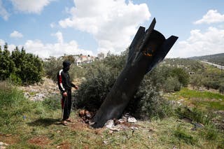 A person stands next to remnants of a missile stuck in the ground found in Kifl Haris village, near Nablus in the Israeli-occupied West Bank, March 24, 2026